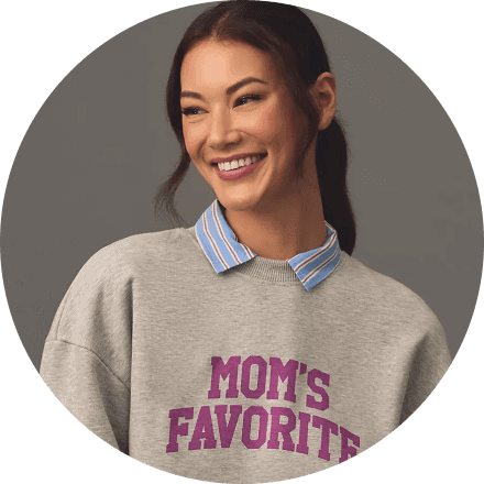 امرأة تبتسم وترتدي سترة رمادية مع عبارة "Mom's Favorite" في خلفية رمادية.